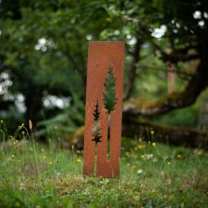 A metal sculpture of trees in the grass.