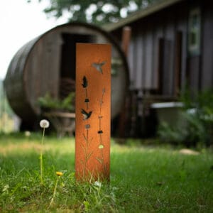 A wooden post in the grass near some weeds.
