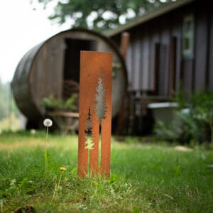 A rusted metal object in the grass near a building.