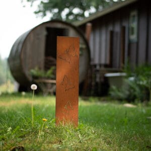 A tall metal pole in the grass near a building.