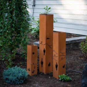 A group of four tall metal sculptures in the grass.