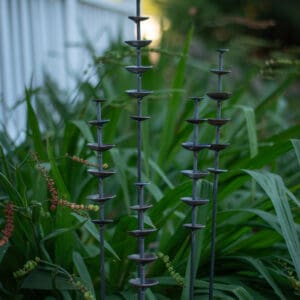 Stacked disc metal garden stakes among greenery